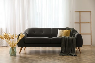 Stylish living room interior with comfortable grey sofa and beautiful spikelets