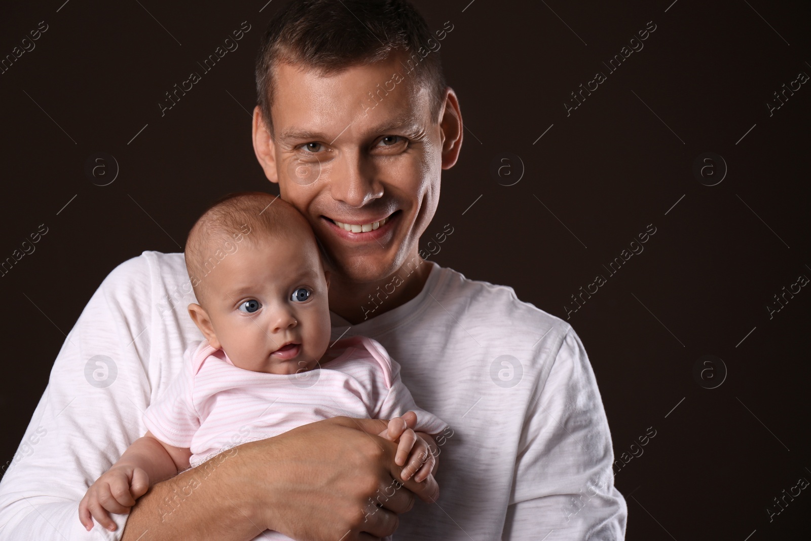 Photo of Happy father with his little baby on dark background