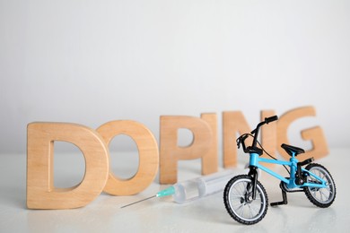 Photo of Word Doping, syringe and bicycle model on light background