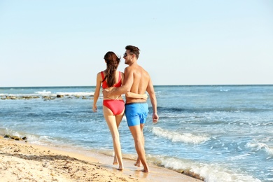 Happy young couple walking together on beach