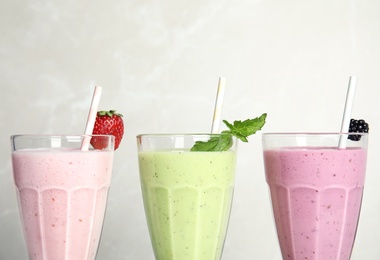 Photo of Tasty milk shakes with fresh berries and mint on light background, closeup