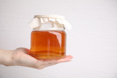 Photo of Woman holding glass jar of tasty kombucha on white background, closeup