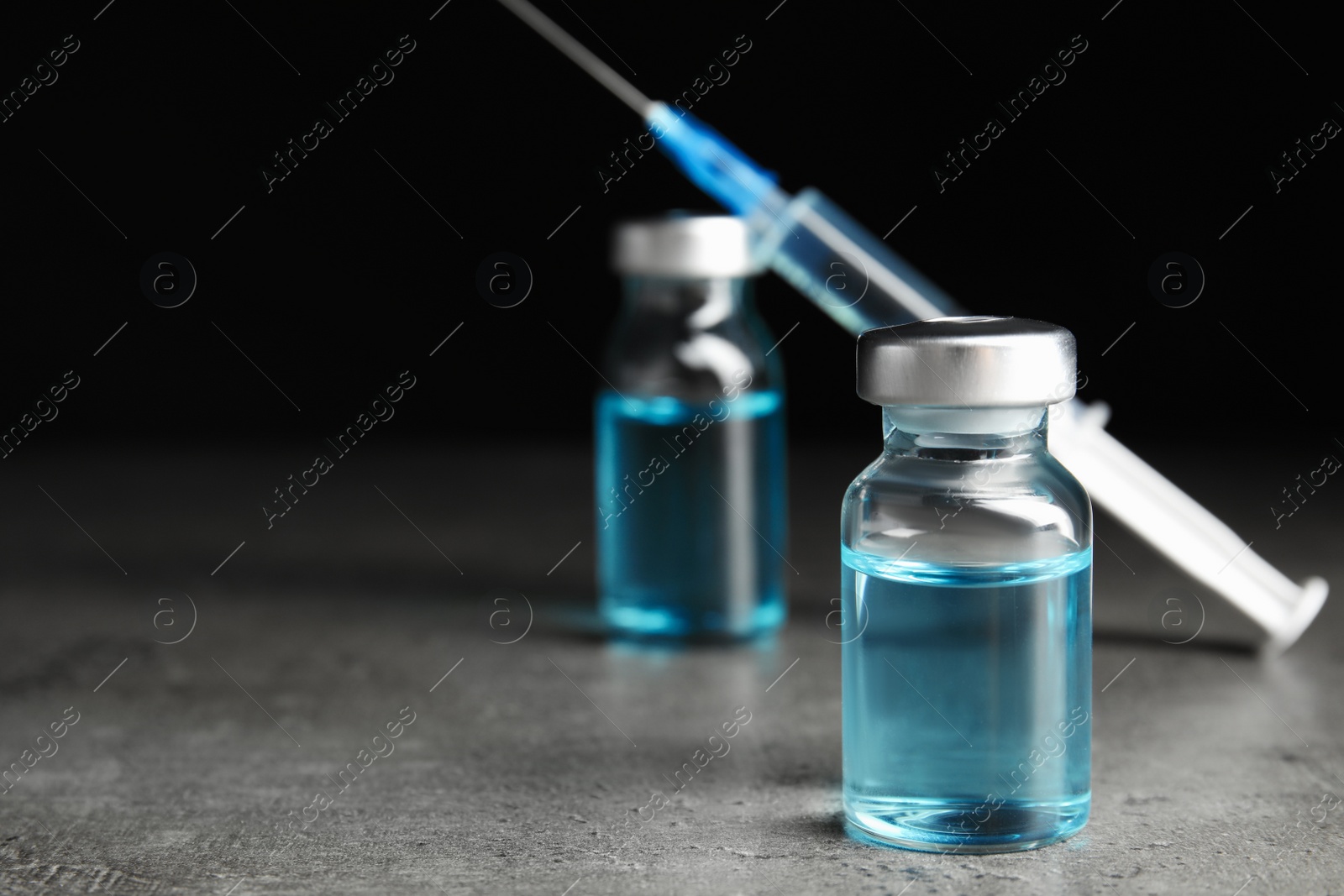 Photo of Vials and syringe on grey table. Vaccination and immunization