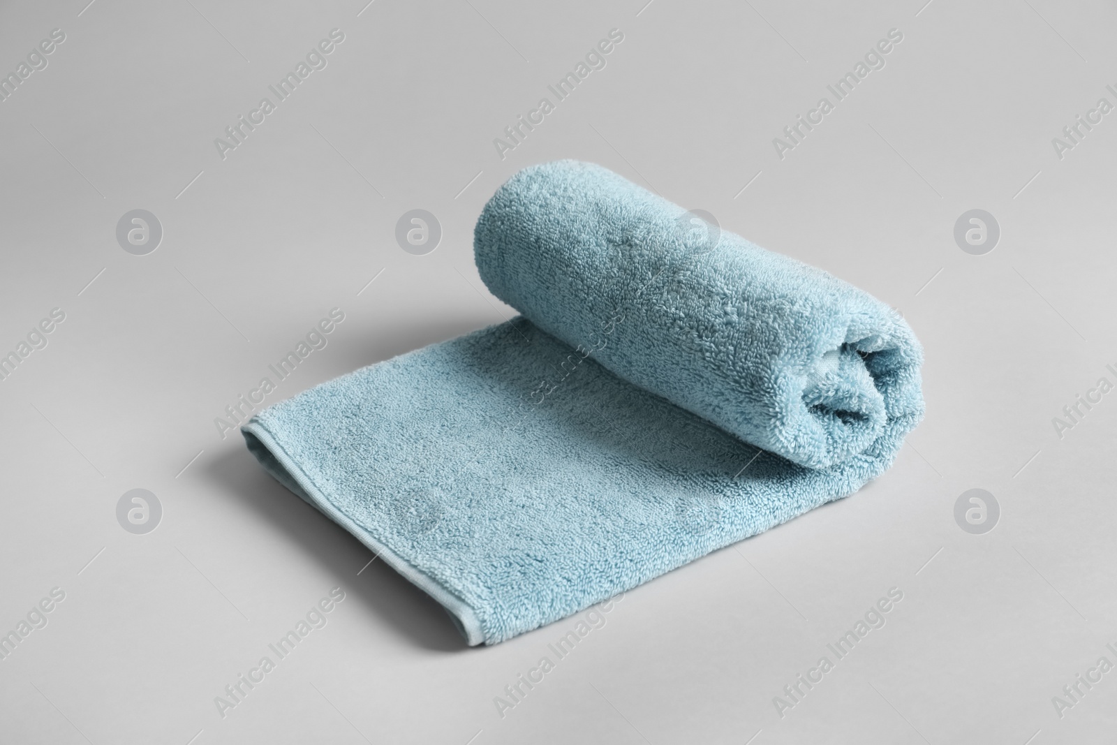 Photo of Fresh fluffy rolled towel on grey background