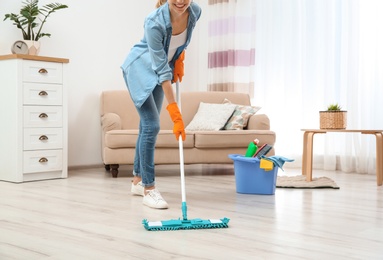 Photo of Young woman washing floor with mop in living room, closeup. Cleaning service