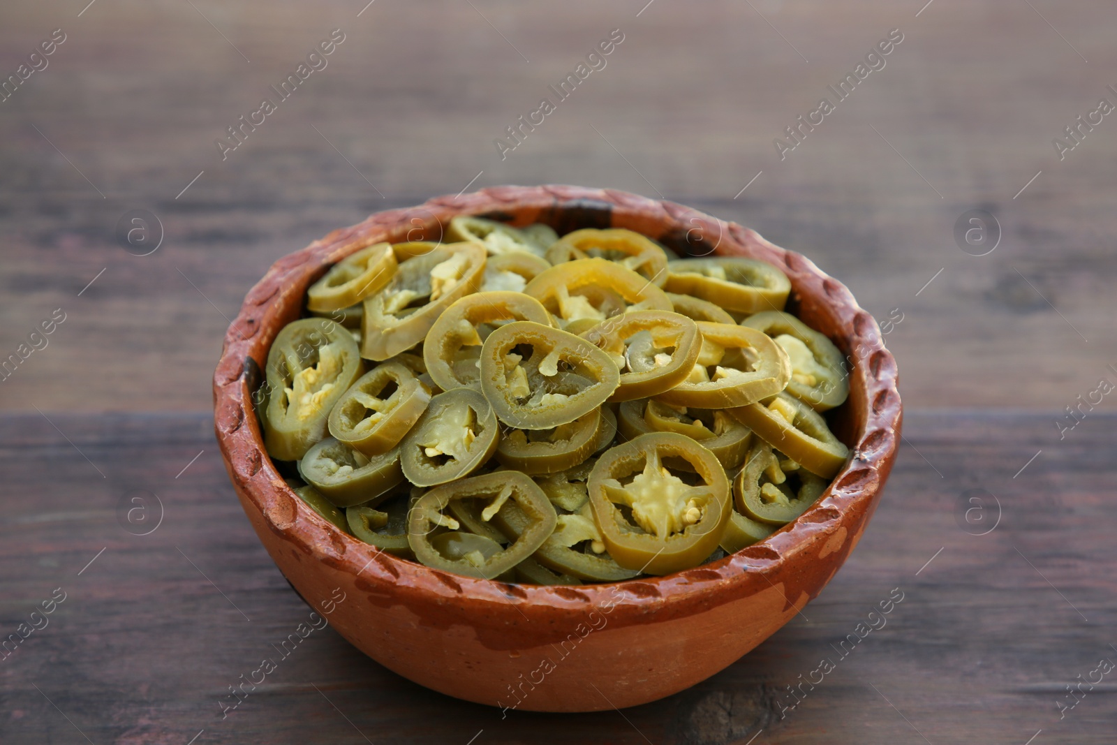 Photo of Pickled green jalapeno peppers on wooden table, closeup