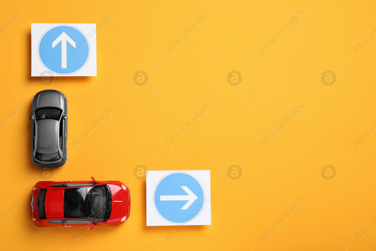 Photo of Toy cars and road signs on yellow background, flat lay. Space for text