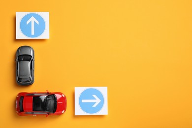 Photo of Toy cars and road signs on yellow background, flat lay. Space for text