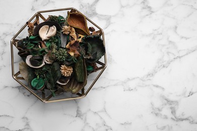 Photo of Aromatic potpourri of dried flowers in bowl on white marble table, top view. Space for text
