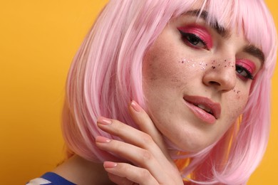 Photo of Beautiful woman with bright makeup and glitter freckles on yellow background, closeup