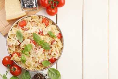 Plate of delicious pasta with tomatoes, basil and parmesan cheese near ingredients on white wooden table, flat lay. Space for text