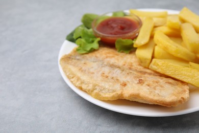 Photo of Delicious fish and chips with ketchup and lettuce on gray table, closeup. Space for text