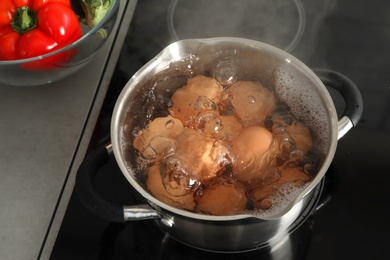 Cooking chicken eggs in pot on electric stove at kitchen