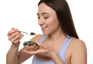 Happy woman eating tasty granola with fresh berries on white background