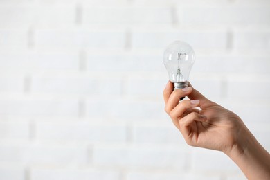 Photo of Woman holding light bulb on white background, closeup. Space for text