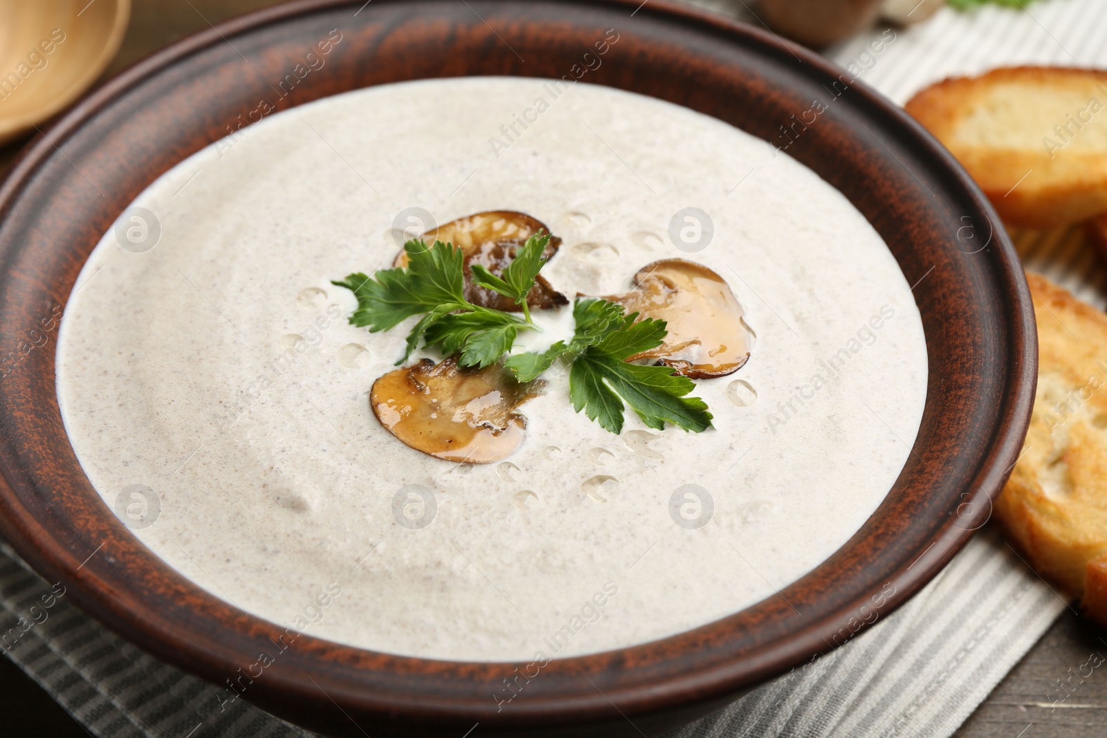 Photo of Fresh homemade mushroom soup in ceramic bowl on wooden table, closeup