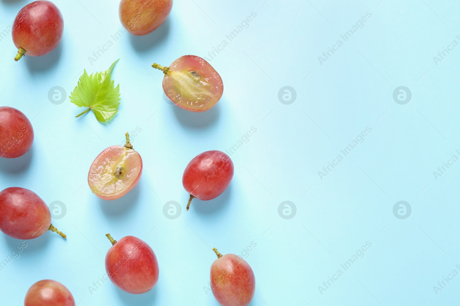 Photo of Flat lay composition with fresh ripe juicy grapes on light blue background, space for text