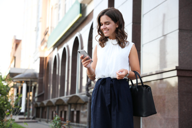 Photo of Young woman with smartphone on city street