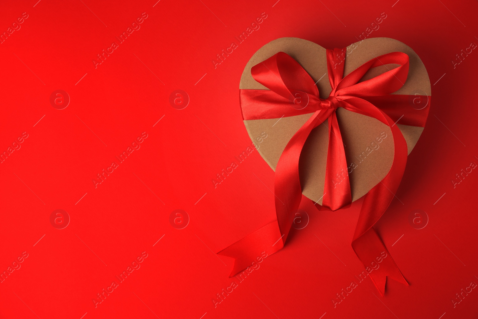 Photo of Beautiful heart shaped gift box with bow on red background, top view. Space for text