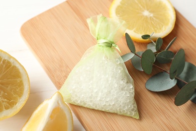 Photo of Scented sachet with aroma beads, eucalyptus branch and lemon on white wooden table, closeup