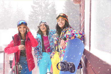 Photo of Friends with skis and snowboards wearing winter sport clothes outdoors