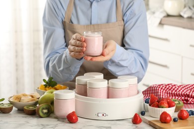 Photo of Woman making tasty yogurt at white marble table in kitchen, closeup