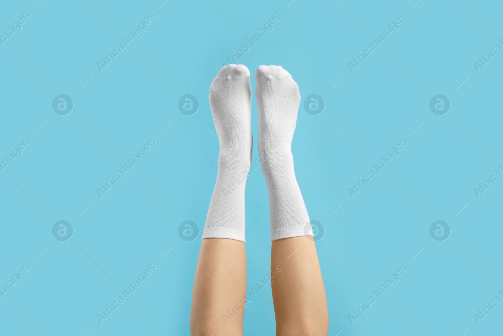 Photo of Woman in stylish white socks on light blue background, closeup