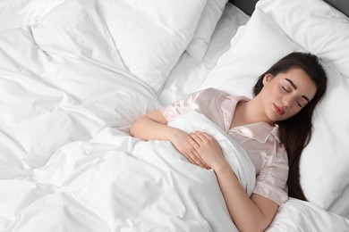 Photo of Beautiful young woman sleeping in soft bed, above view