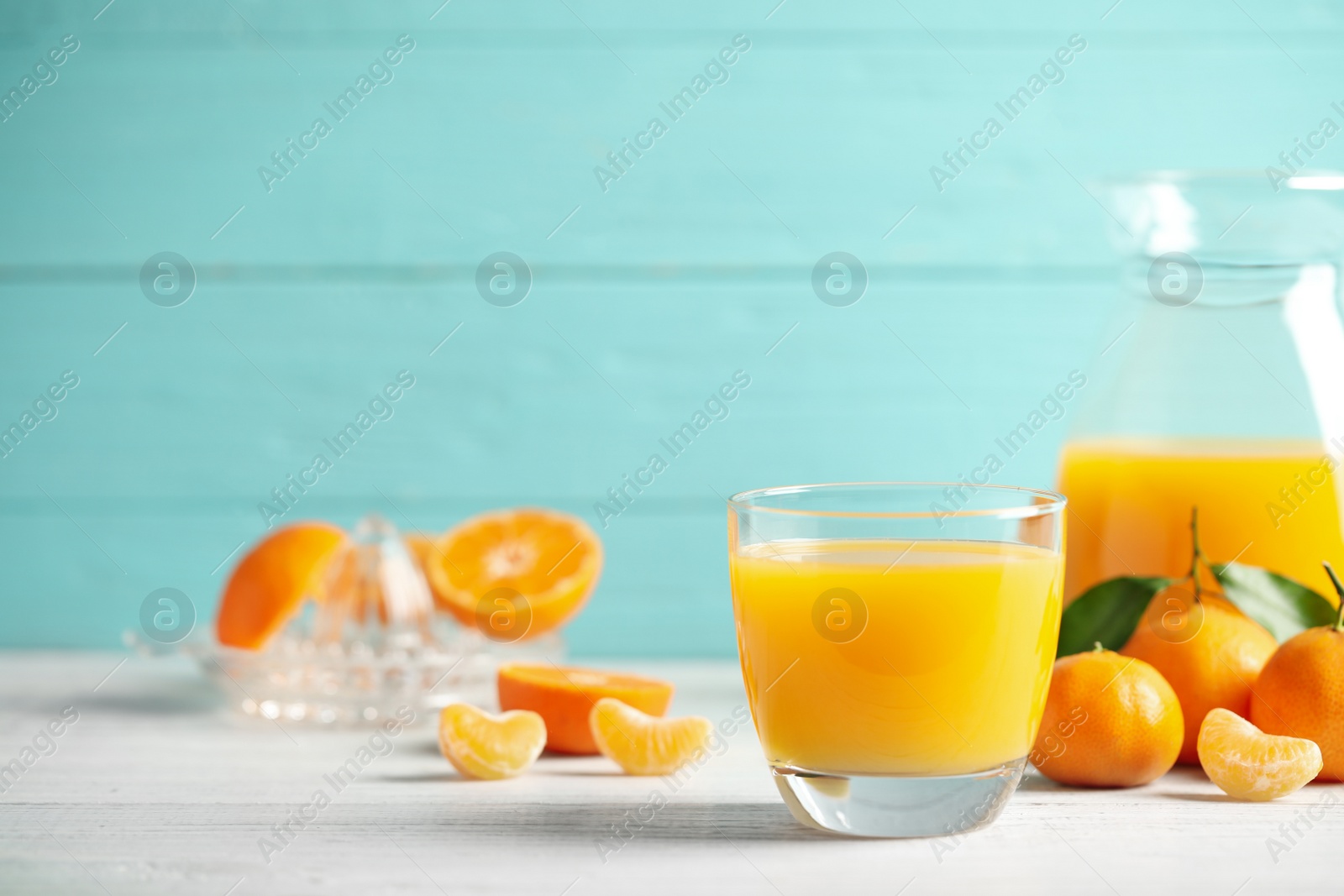 Photo of Glass of fresh tangerine juice and fruits on white wooden table. Space for text