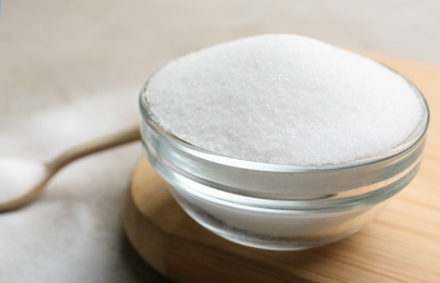 Glass bowl with salt on wooden board, closeup