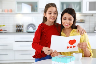 Photo of Daughter congratulating her mom in kitchen, space for text. Happy Mother's Day