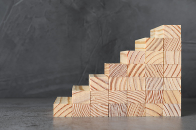 Photo of Steps made with wooden blocks on table against grey background, space for text. Career ladder