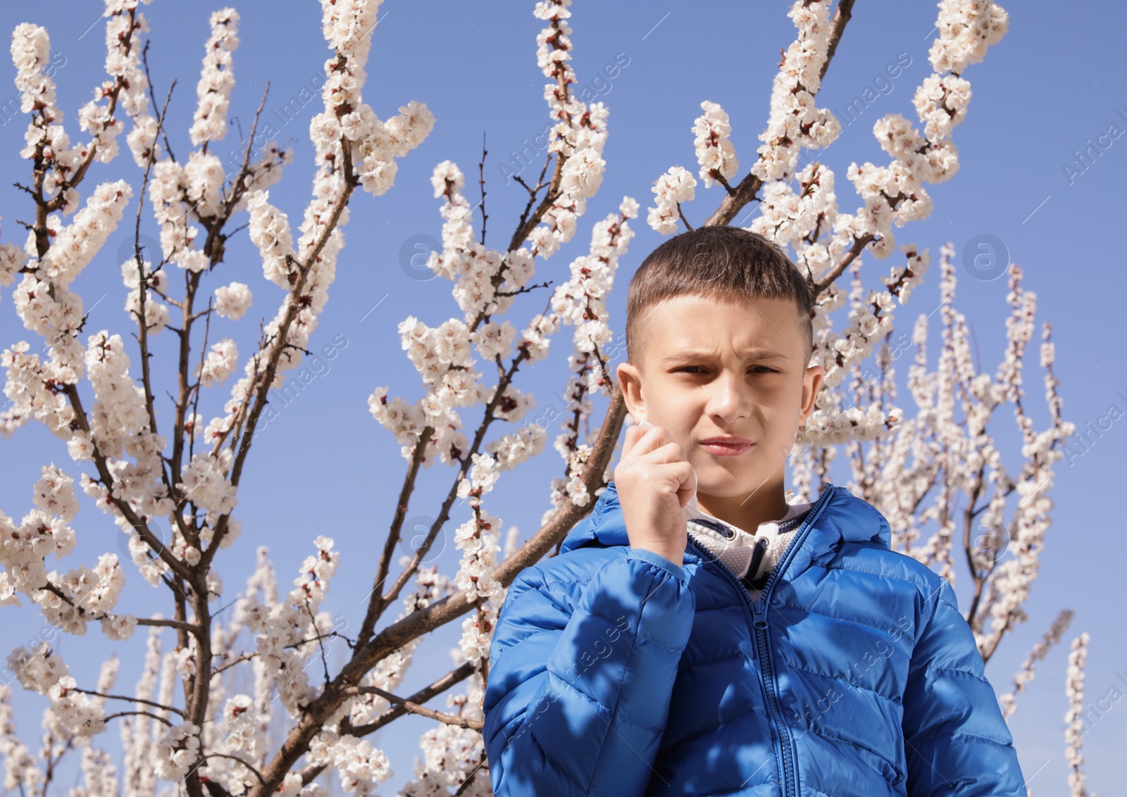 Photo of Little boy suffering from seasonal allergy outdoors on sunny day, space for text