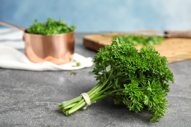 Photo of Fresh green parsley on grey table against color background, space for text