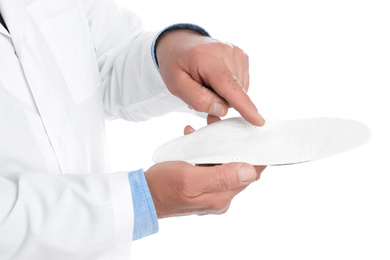 Photo of Male orthopedist showing insole on white background, closeup