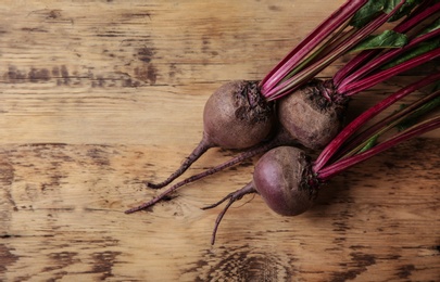 Fresh beets with leaves on wooden table, flat lay. Space for text