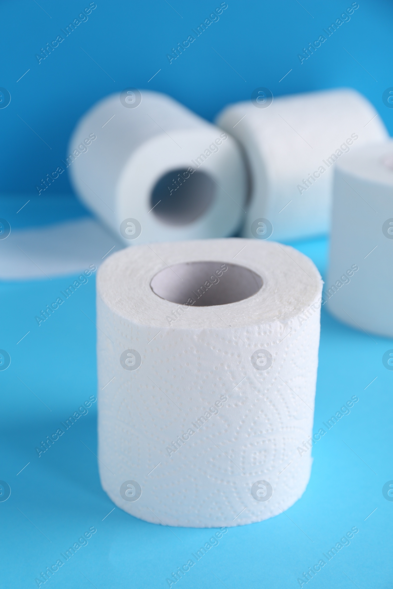 Photo of Soft toilet paper rolls on light blue background, closeup