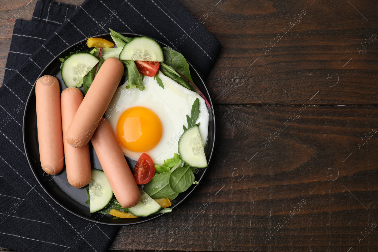 Photo of Delicious breakfast with boiled sausages and fried egg on wooden table, top view. Space for text