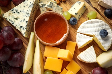 Different kinds of delicious cheese and snacks on wooden background, top view