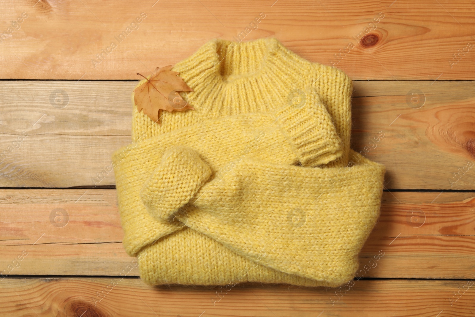 Photo of Warm sweater and dry leaf on wooden background, top view. Autumn season