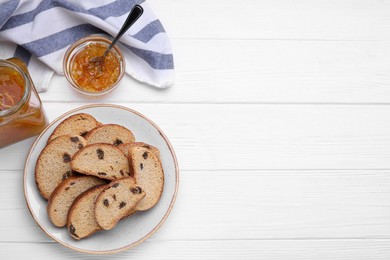 Photo of Plate of sweet hard chuck crackers with raisins and jam on white wooden table, flat lay. Space for text