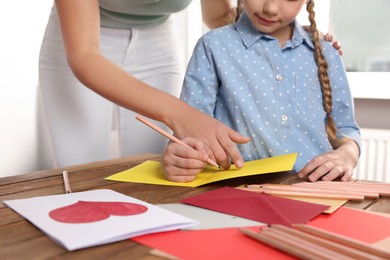 Photo of Little girl with her mother making beautiful greeting card at home, closeup