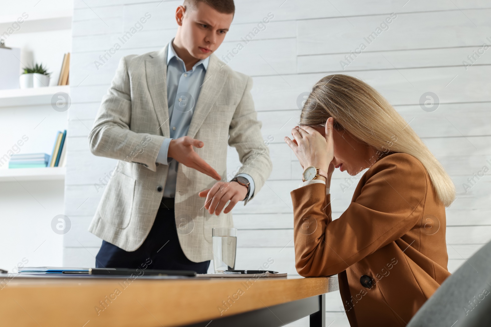 Photo of Businessman pointing on wrist watch while scolding employee for being late in office