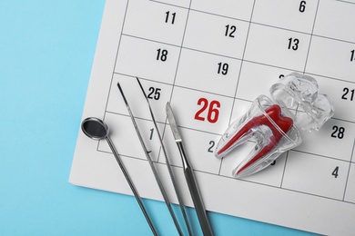 Photo of Flat lay composition with dentist tools, tooth model and calendar on color background