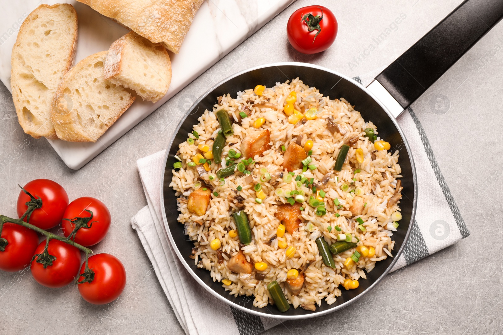 Photo of Delicious rice pilaf with chicken and vegetables on light grey table, flat lay