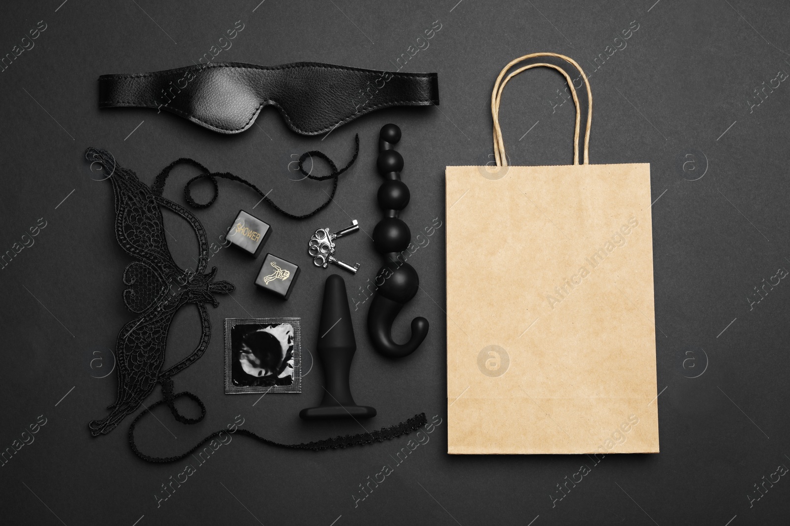 Photo of Shopping bag and different sex toys on black background, flat lay