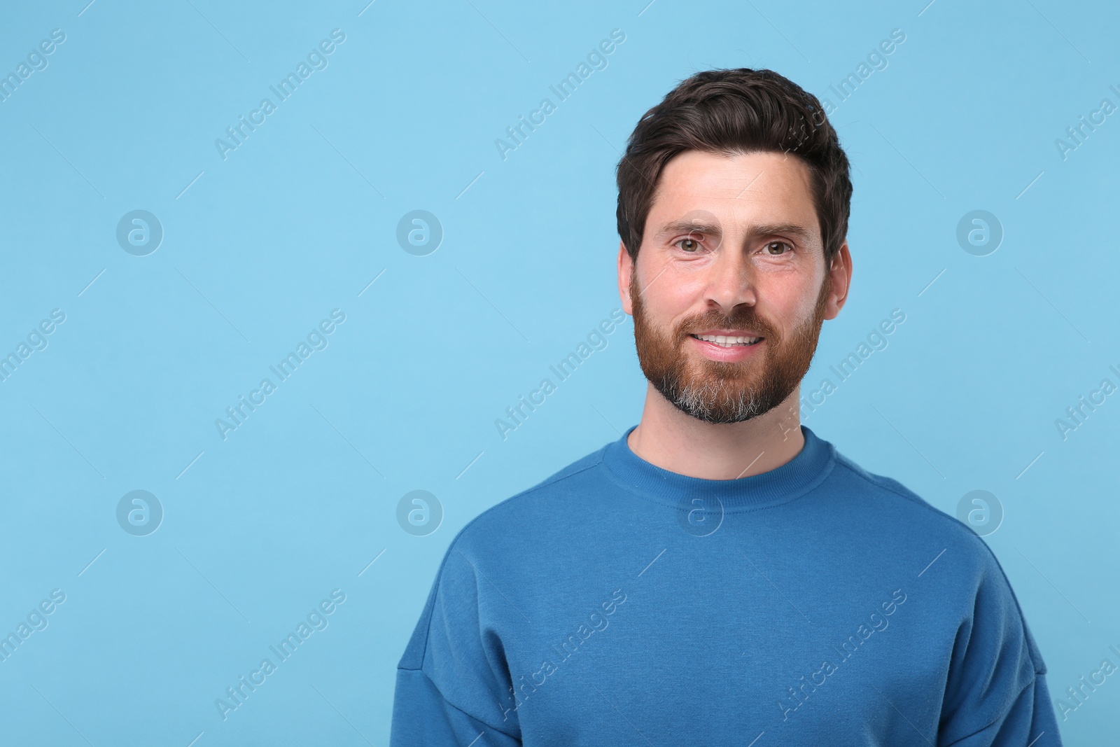 Photo of Portrait of handsome man on light blue background, space for text