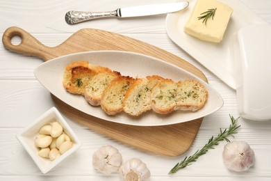 Photo of Tasty baguette with garlic and dill served on white wooden table, flat lay