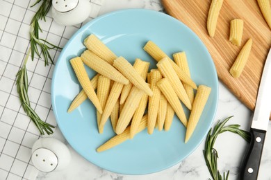 Fresh baby corn cobs on white marble table, flat lay