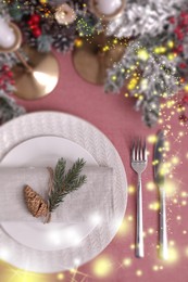 Image of Christmas place setting for festive dinner on pink table, flat lay. Bokeh effect